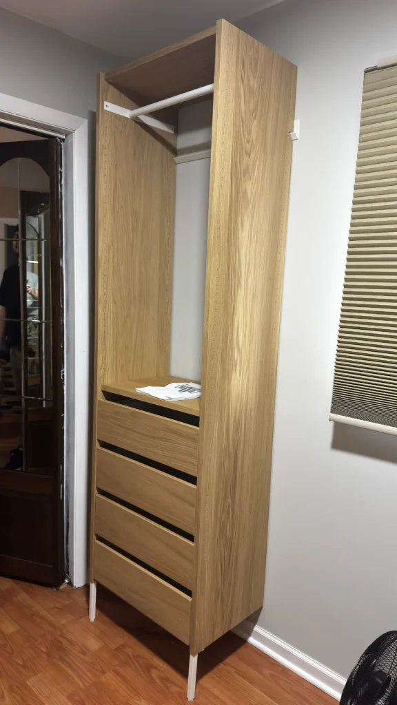 Side view of IKEA AURDAL closet organizer with wood-look panels, hanging rod and four drawers