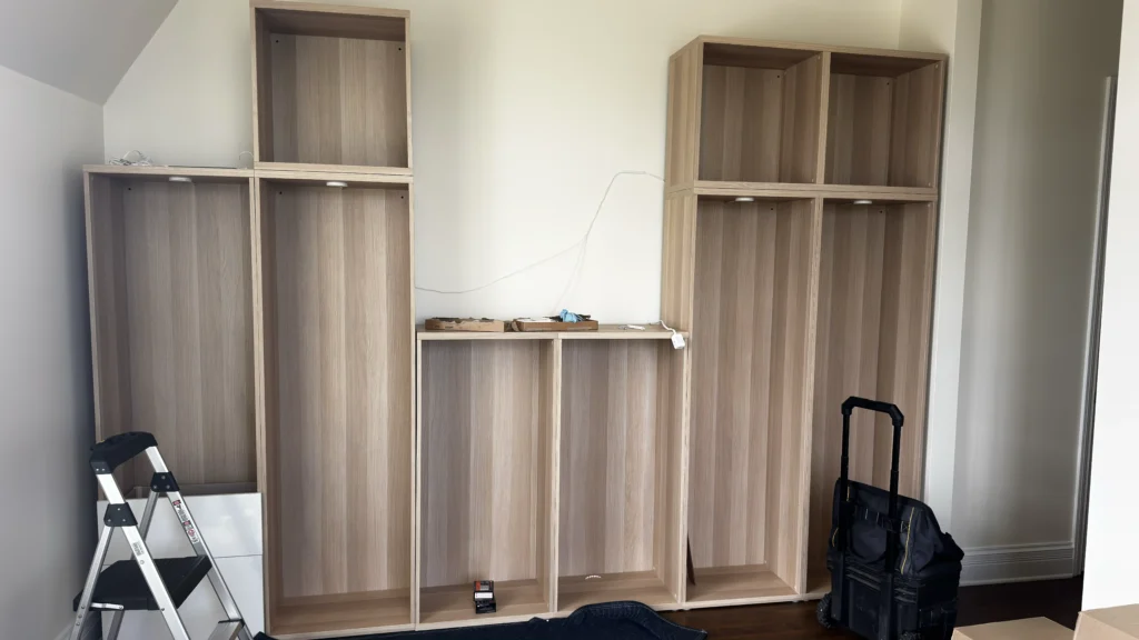 Partially installed IKEA BESTÅ wall unit with white drawers and glass cabinet doors in Palatine, IL.