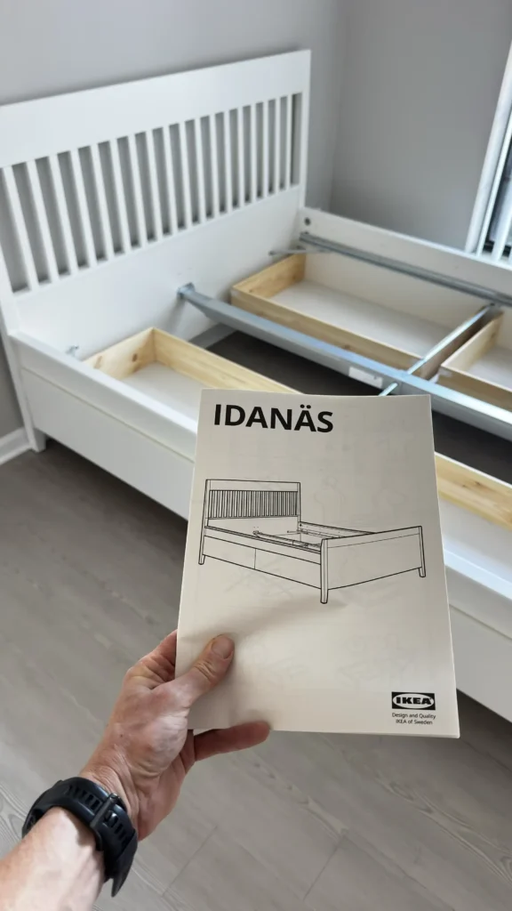 White IKEA IDANÄS bed frame during assembly with instruction booklet in Palatine, IL