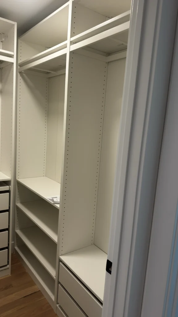 White IKEA PAX closet with hanging sections, open shelves and drawers fitted into a narrow room in Lake Forest, IL.