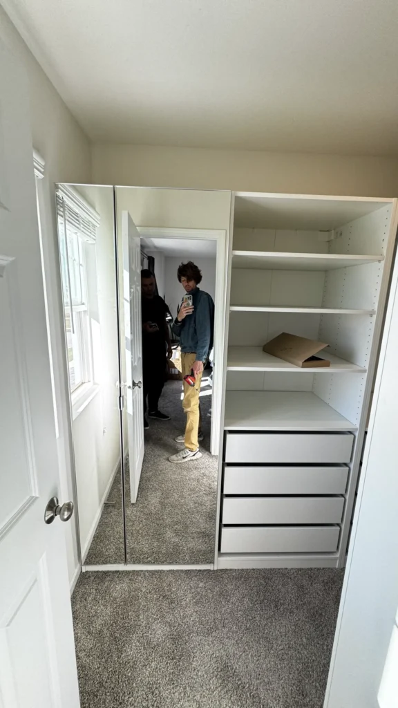IKEA PAX mirrored wardrobe doors next to a white shelving unit with four drawers in Buffalo Grove, IL.