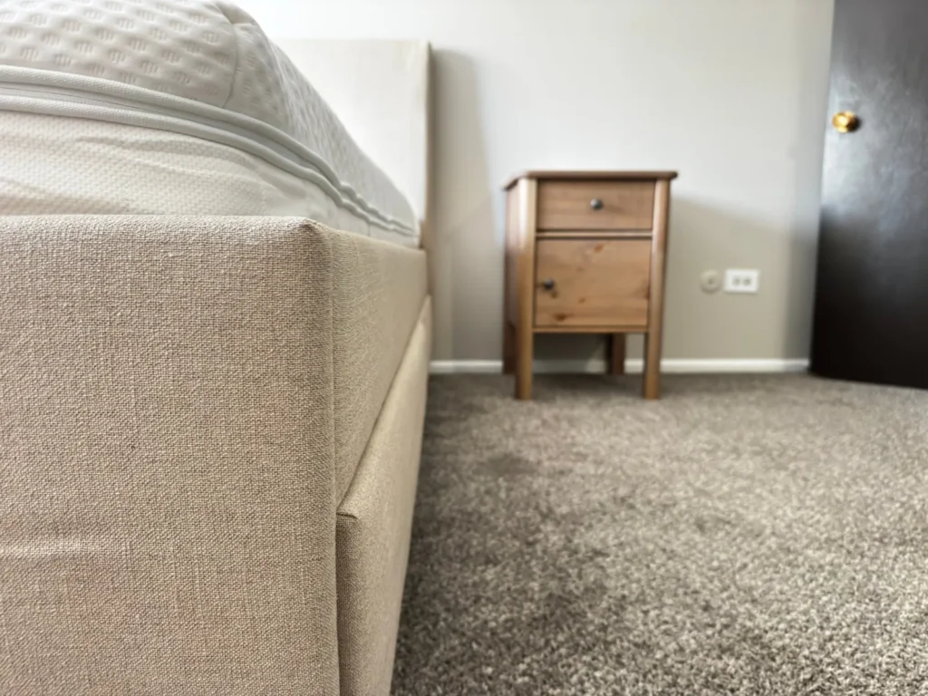 Close-up of assembled IKEA upholstered bed frame and pine nightstand, Arlington Heights, IL